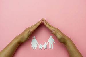 Top view of Hands protect chain family paper on pink background. Family care insurance concept,love and charity .